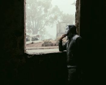 Rear view of woman standing by window