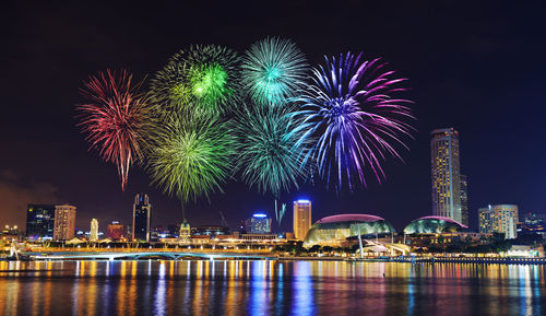 Firework display over illuminated buildings in city at night