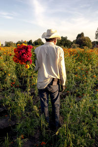 Mexican farmer carrying orange and cherry cempasuchil flowers