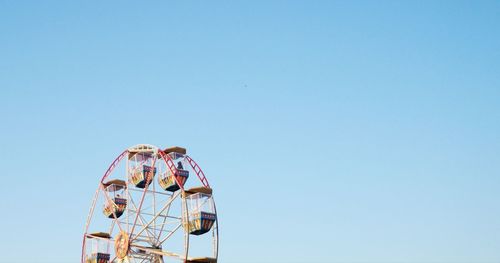 Low angle view of ferris wheel against clear blue sky