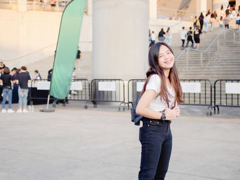 Portrait of young woman standing against wall