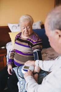 Senior man checking blood pressure of his wife at home