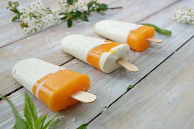 Close-up of popsicles with flowers on wooden table