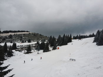 People skiing on snow field against sky