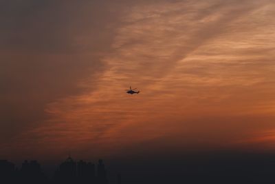 Low angle view of silhouette airplane against sky during sunset