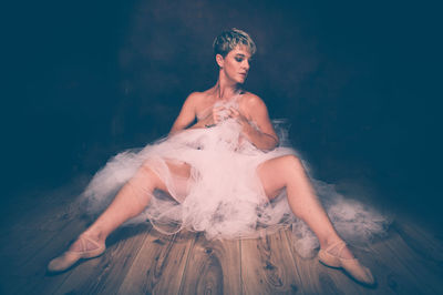 Semi-naked woman wearing tulle tutu against black background