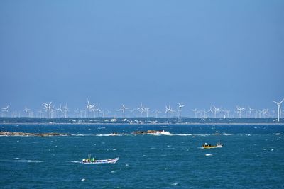 Sailboats in sea against clear blue sky