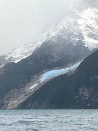 Scenic view of sea and snowcapped mountains against sky