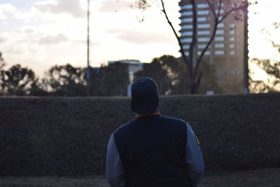 Rear view of man standing in city during sunset