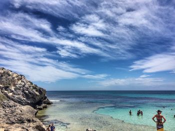 People at beach against cloudy sky