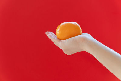 Midsection of person holding ice cream against red background