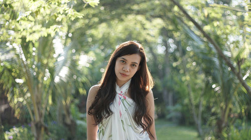 Young woman standing against trees