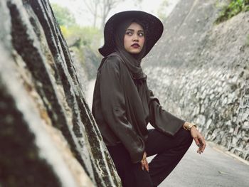 Woman wearing hat looking away while standing outdoors