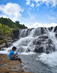 Rear view of man surfing in waterfall