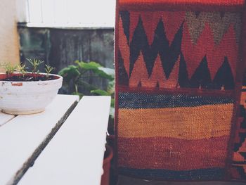 Close-up of carpet drying on clothesline by potted plant