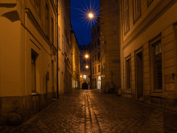 Illuminated street amidst buildings at night