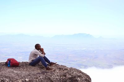 Rear view of man sitting on rock