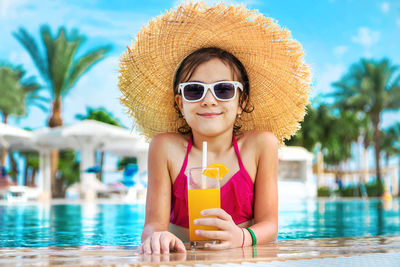 Smiling girl with orange glass at poolside