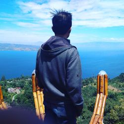 Rear view of man looking at sea against sky