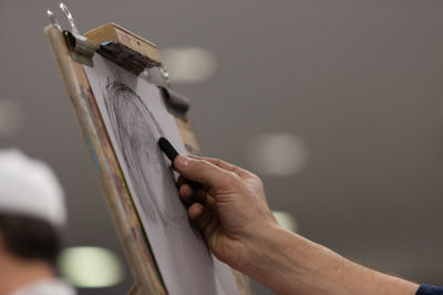 Cropped hand of person drawing on artist canvas