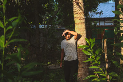 Full length of woman standing by plants in forest