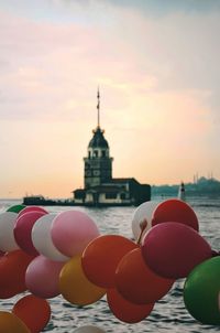 Multi colored balloons in building against cloudy sky