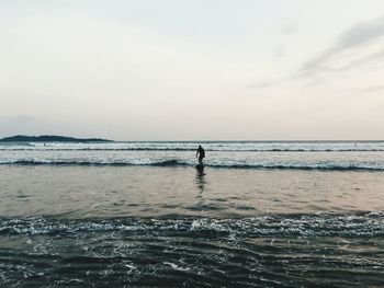 Silhouette man standing on beach against sky during sunset