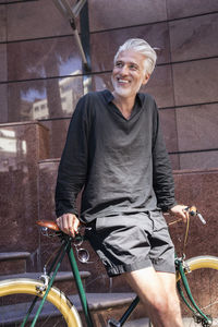 Mature man in the city leaning on his bicycle