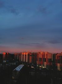 Illuminated buildings in city against sky during sunset