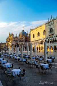 Chairs and tables at sidewalk cafe against buildings in city