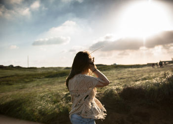 Rear view of woman standing by field during sunset