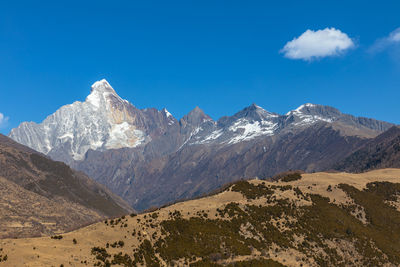 Scenic view of snowcapped mountains against blue sky