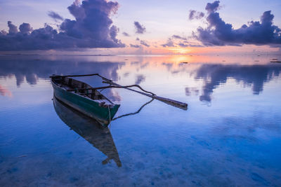 Boat in lake against sky during sunset