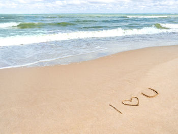Sea coast with surf. words i love you and heart symbol written on sandy beach. vacation on seaside.