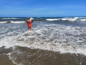 Rear view of man standing on beach against sky