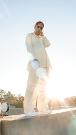 Portrait of young woman standing against clear sky