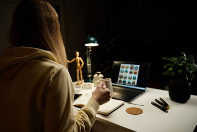 Woman at home workplace using laptop at night