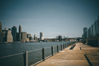 Modern buildings by river against sky in city