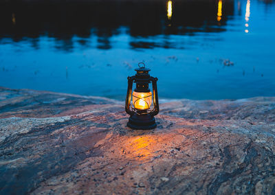 Close-up of illuminted lantern by sea