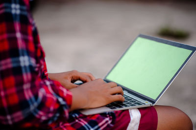 Close-up of person using laptop outdoors