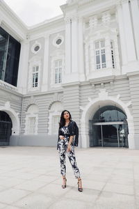 Young woman looking away while standing against building