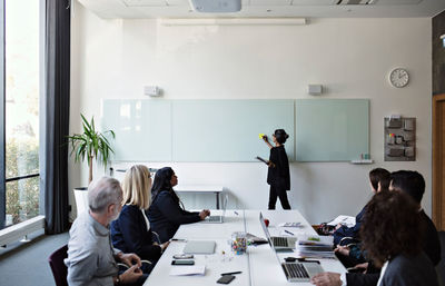 Colleagues concentrating on businesswoman giving presentation during meeting in office