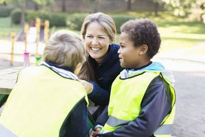 Happy teacher with children in reflective jacket