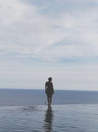 Rear view of man looking at sea against sky