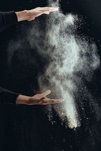 Cropped hands of man with chalk against black background