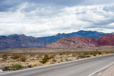 Scenic view of road by mountains against sky