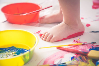 Low section of child standing by paints