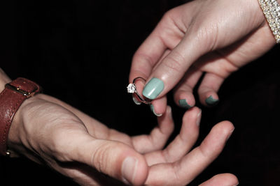 Cropped hand of woman giving ring to man