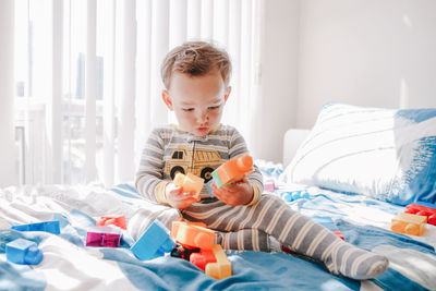 Cute boy with toy on bed at home