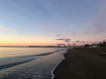 Scenic view of beach against sky at sunset